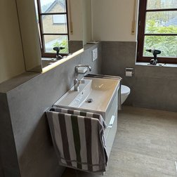 Das Badezimmer verfügt über große Fenster, die Tageslicht hereinlassen, und eine stilvolle Einrichtung in neutralen Tönen.